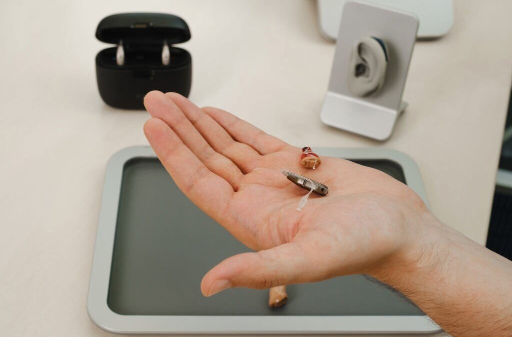 Modern miniature hearing aids. Small and discreet invisible hearing aids in hands. Closeup of patient.