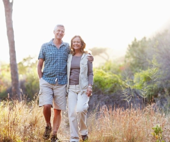 Happy couple walking together outdoors in a sunny natural setting